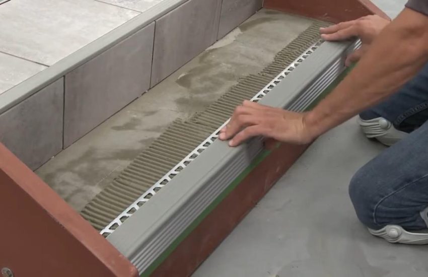 Man installing stair nosing on tile stairs